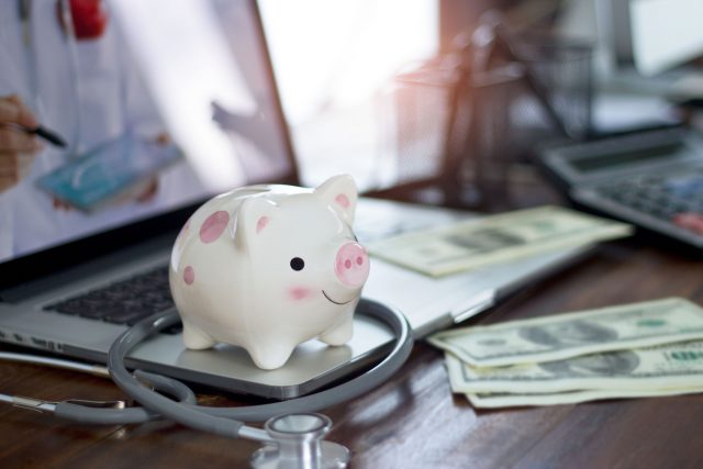 Piggy bank and stethoscope on computer laptop, money savings, medical insurance and health care financial and money savings.
